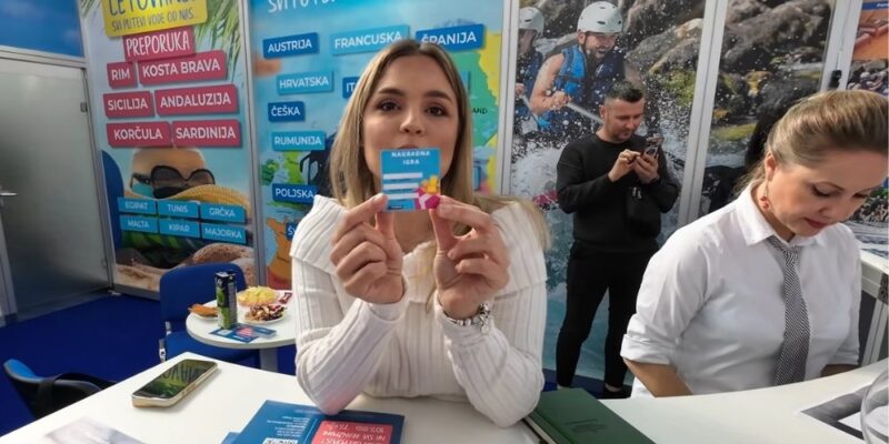 Predstavnica kompanije promoviše sajamsku nagradnu igru na promotivnom štandu